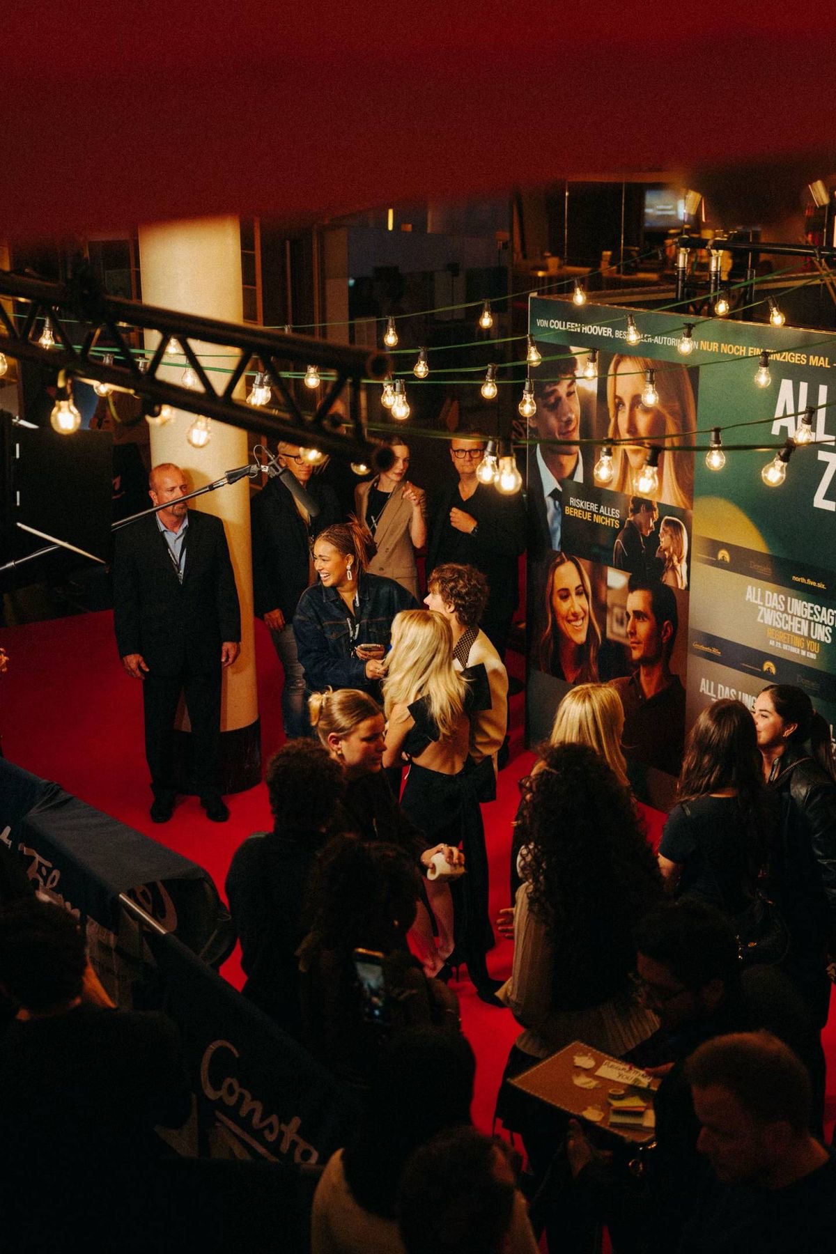 A discreet linen catering table with carafes and cups beside cinema lighting stands on a film set