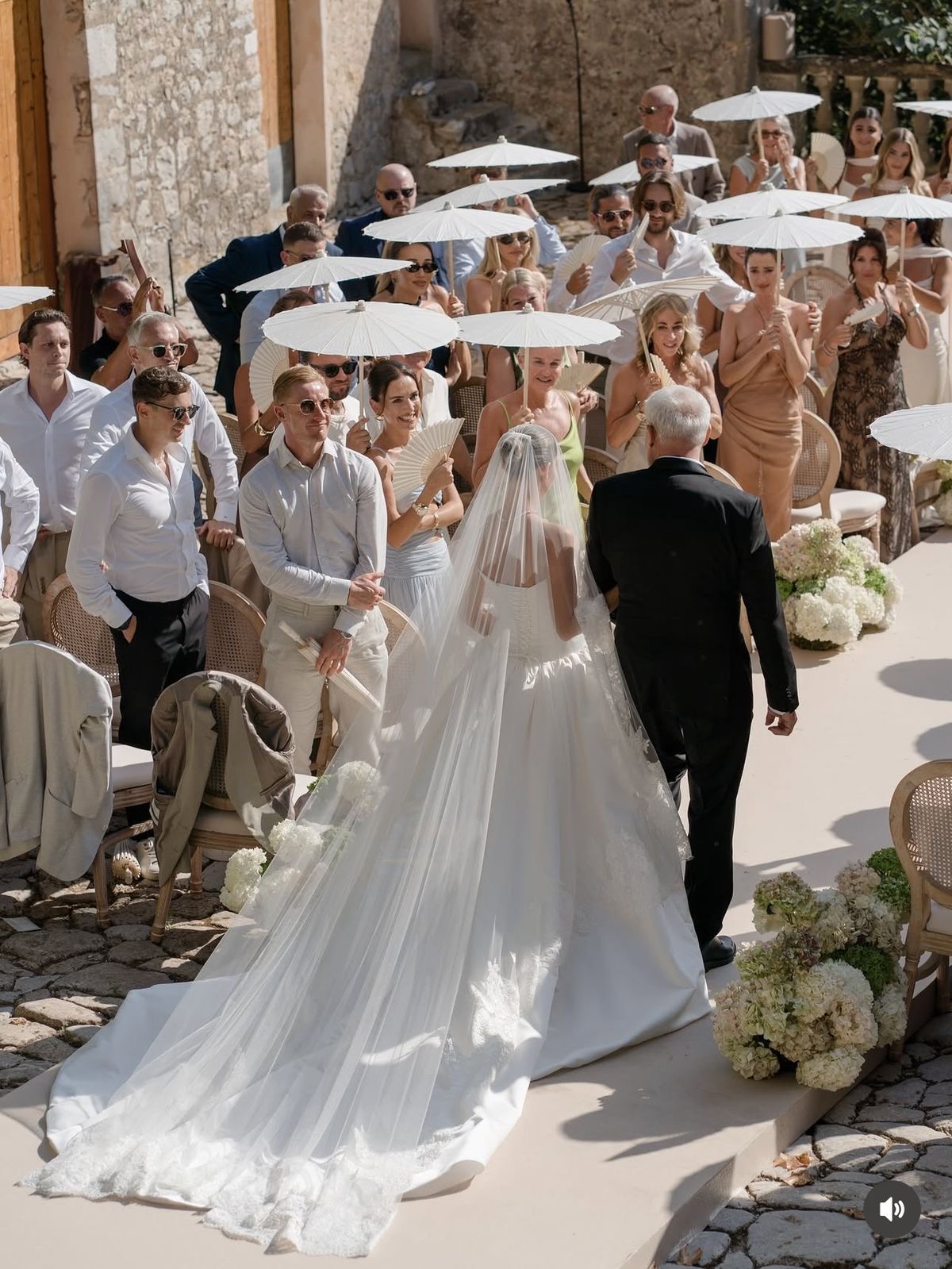 An elegant outdoor wedding reception table dressed in ivory linen, cascading green grapes, white roses and abundant grazing displays in garden light