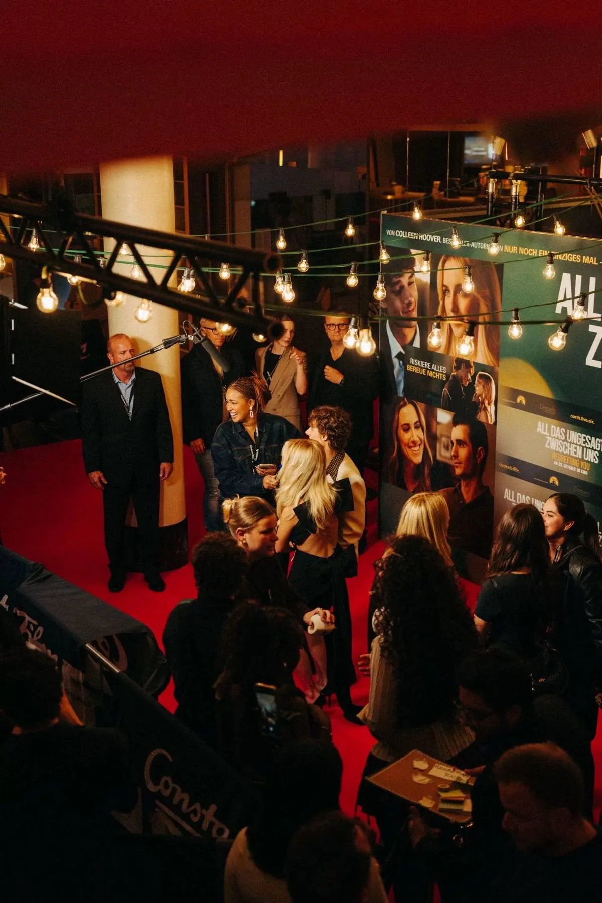 A discreet linen catering table with carafes and cups beside cinema lighting stands on a film set